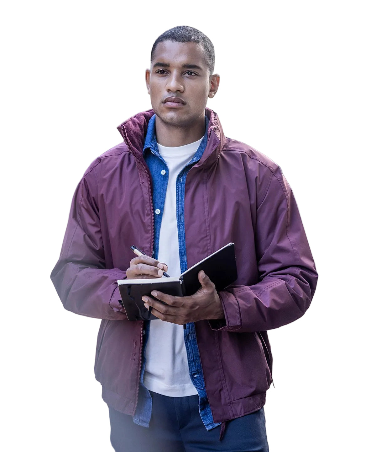 Man in a purple jacket writing in a notebook outdoors