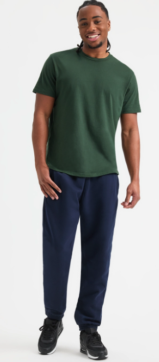 A man modeling a dark green crewneck t-shirt and navy blue sweatpants against a plain white studio background.