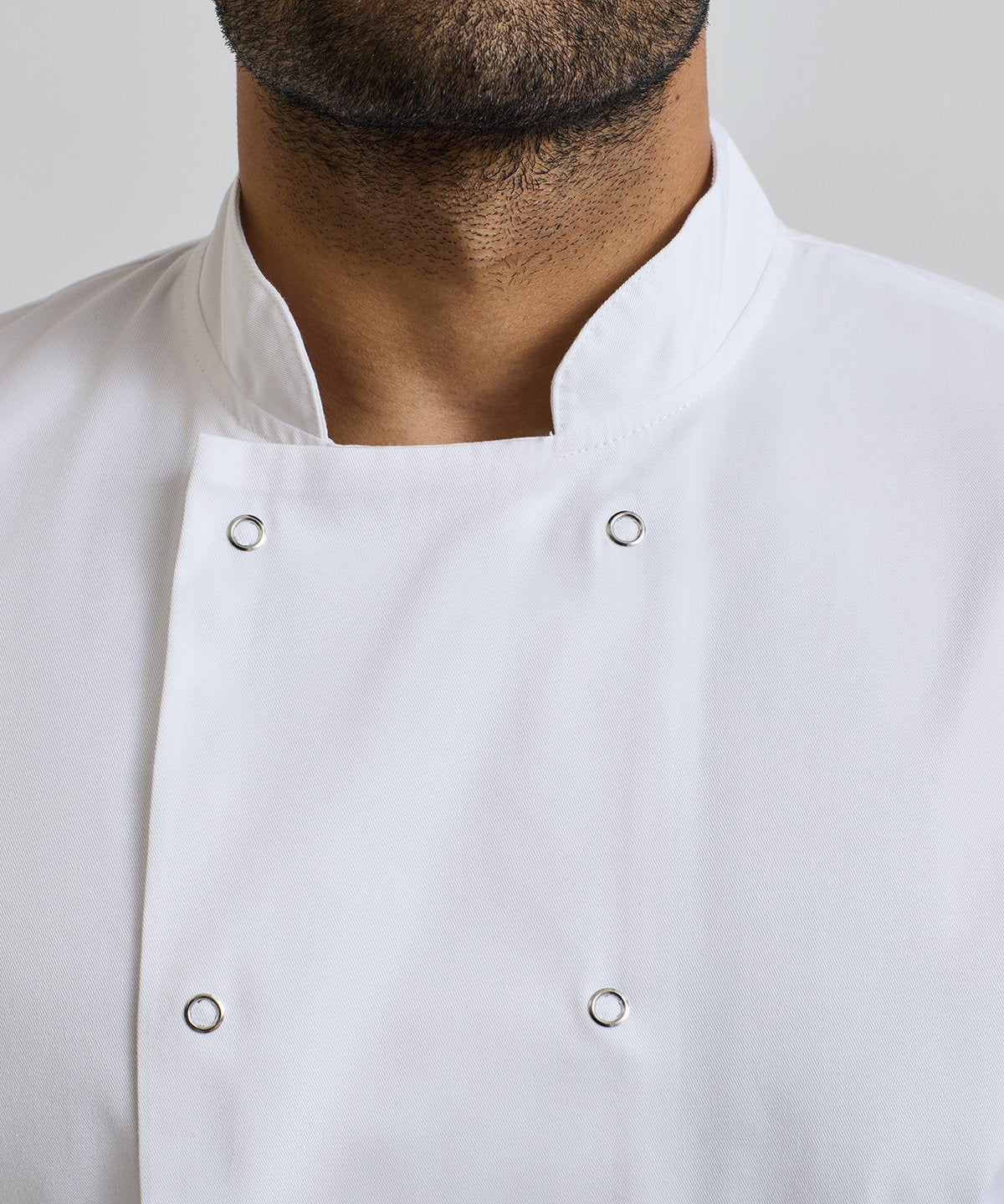 Close-up of a Chef wearing a white chef's coat with buttons on a light gray background