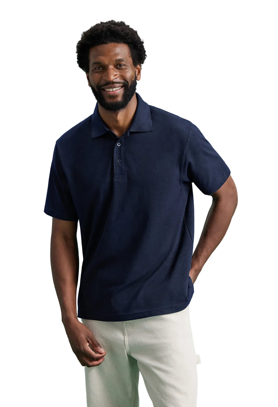 Man wearing a Uneek GR11 navy polo shirt and white pants against a green background